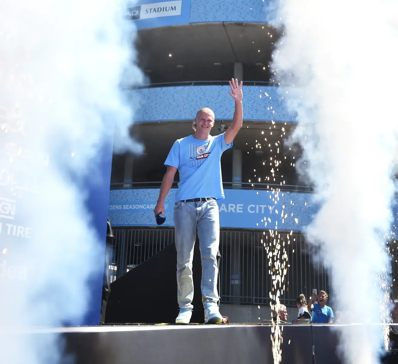 A sports event celebration featuring a footballer waving to fans, with celebratory smoke and confetti.